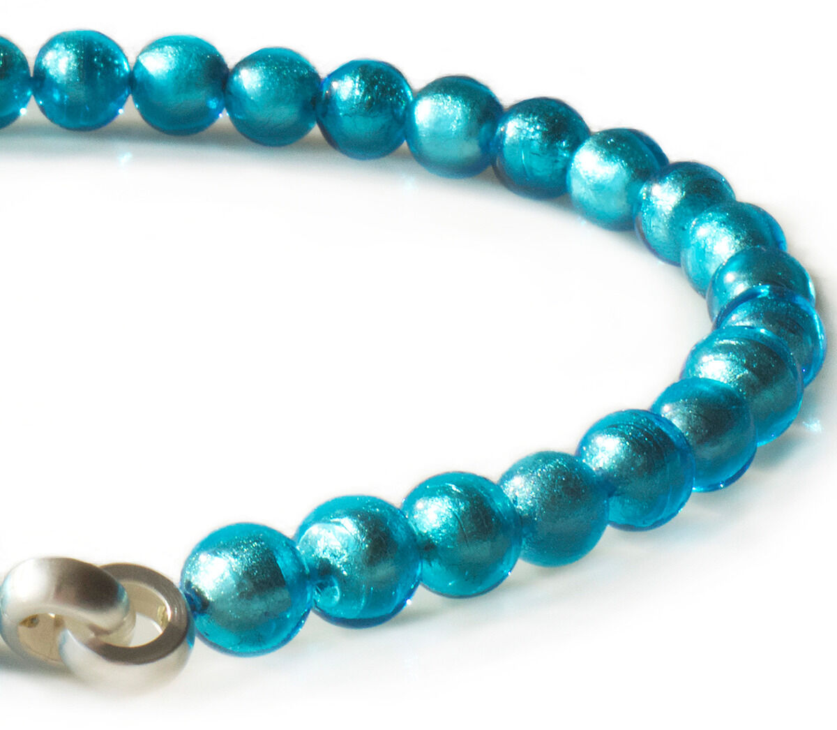 Das Bild zeigt das ZEIT-Sonderediton Collier Muranoglas »Türkis« von Menard. Die Halskette besteht aus glänzenden, runden türkisen Muranoglasperlen und einer silbernen Schließe. Das Collier reflektiert Licht und wirkt hochwertig, exklusiv und stilvoll.