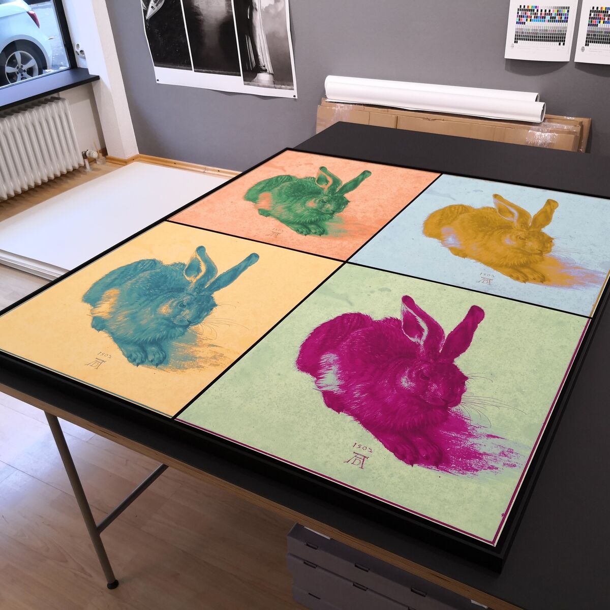 Pop-Art-Druck des 'Dürer Hase Quadrupel' in vier verschiedenen Farbkombinationen auf einem Tisch in einem Künstleratelier.