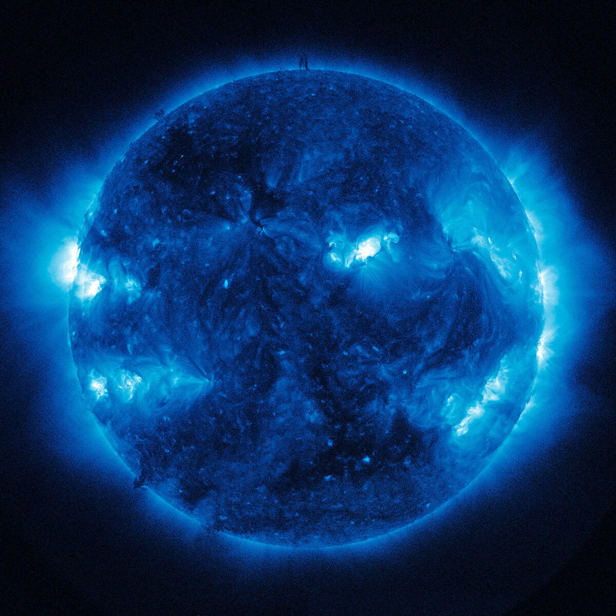 Ein Bild der Sonne, aufgenommen von der NASA und dem Solar Dynamics Observatory. Die Sonne wird in einem lebendigen Blau dargestellt, wobei helle blaue Leuchtstöße und dunklere Bereiche auf der Oberfläche zu sehen sind.