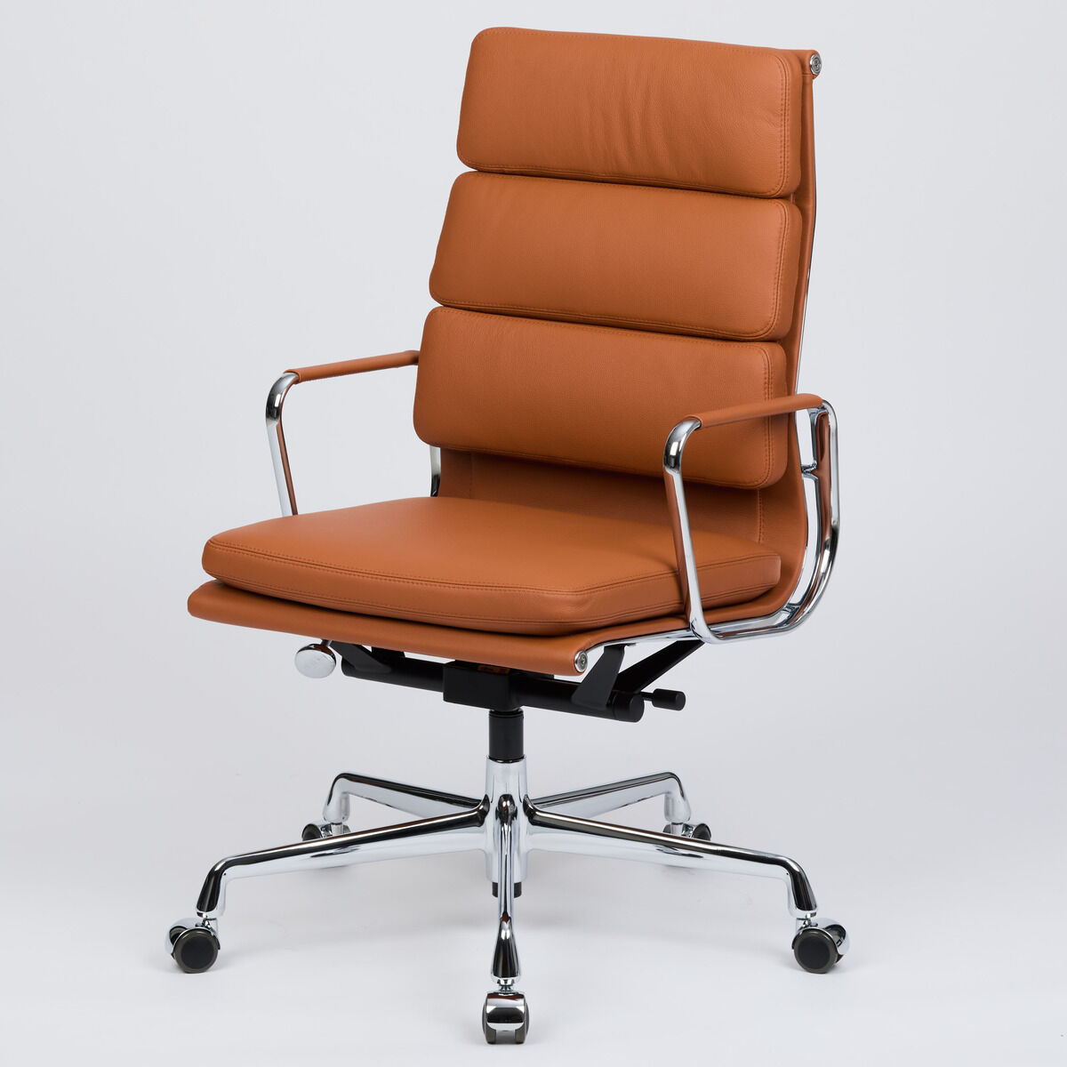 Der Vitra Soft Pad EA219 Schreibtischstuhl in cognacfarbenem Leder, Sonderedition für DIE ZEIT, steht vor hellem Hintergrund. Die hohe Rückenlehne mit drei gepolsterten Kissen, verchromtes Gestell mit fünf Rollen und lederbezogene Armlehnen prägen das elegante Design.