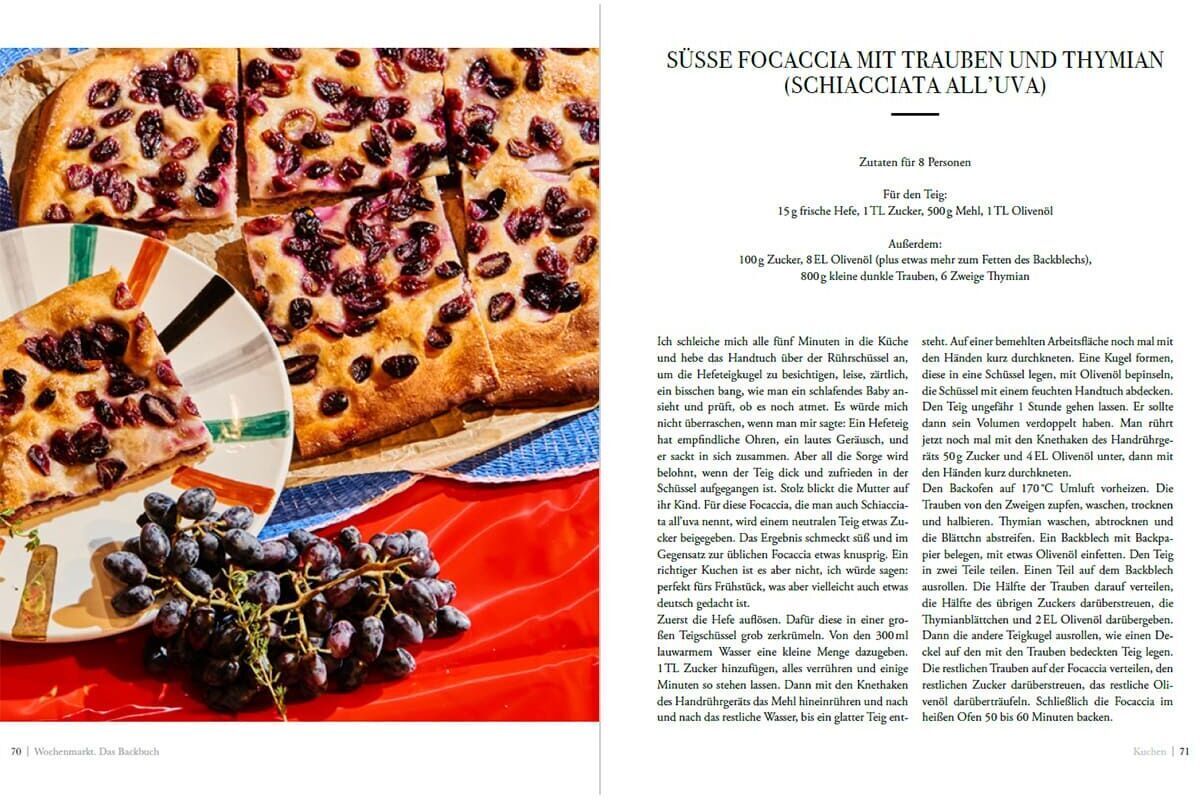 Das Wochenmarkt-Backbuch zeigt auf einer Seite ein Rezept für süßes Focaccia mit Trauben und Thymian. Daneben sind Bilder von geschnittenem Focaccia-Brot und Trauben. Die Seitenränder sind weiß, das Foto zeigt ein braunes und violettes Brot auf einem roten Tuch.