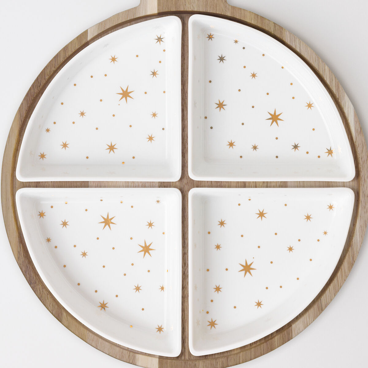 Ein rundes Schalen-Set mit vier weißen Schalen, verziert mit goldenen Sternen, eingebettet in einen Holzrahmen in Kugelform und mit einer kleinen Lederschlaufe am oberen Rand. Die Schalen erinnern an eine stilisierte Weihnachtsbaumkugel. Das Set steht auf einer hellen Oberfläche.