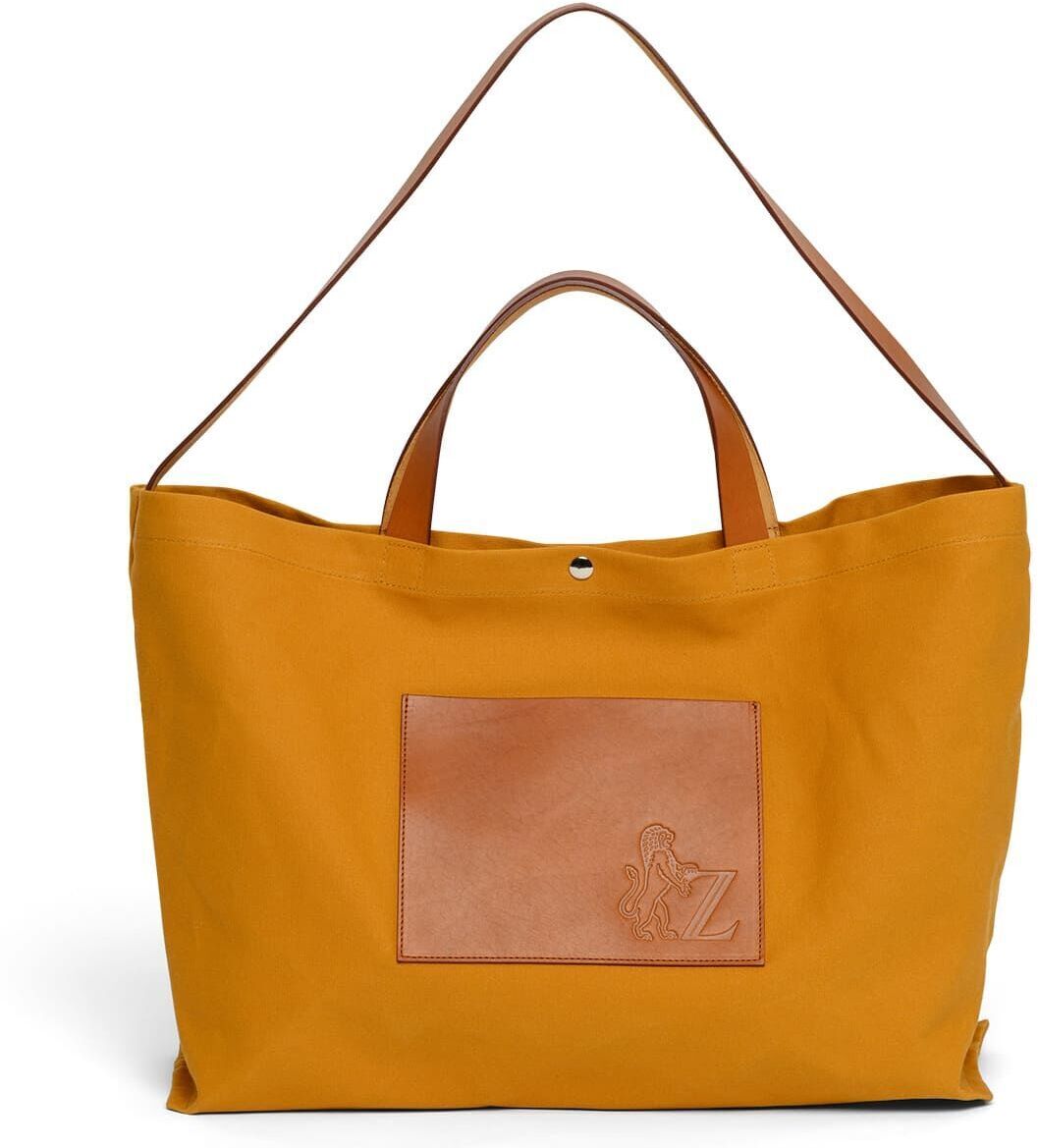 Bild einer Jubiläums-Markttasche in gelber Farbe mit braunen Lederdetails und geräumigem Design. Die Tasche hat kurze und lange Tragegriffe.