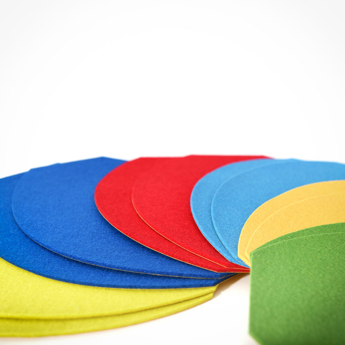 Verschiedenfarbige, übereinander gelegte Pappstücke in den Farben Blau, Rot, Gelb und Grün.