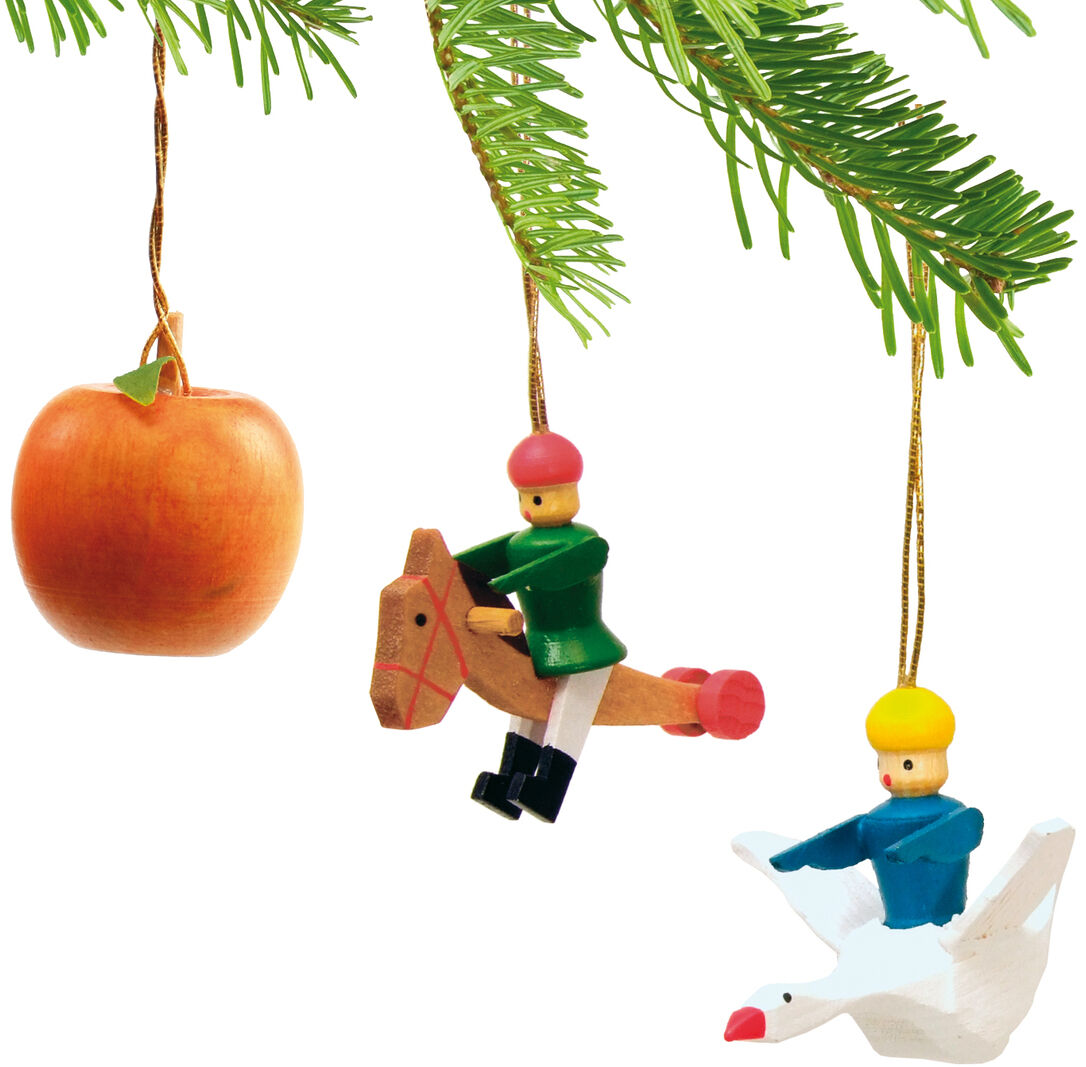 Fünf Holzanhänger hängen an einem grünen Tannenzweig: zwei naturgetreue Äpfel und drei bunte Spielfiguren auf Pferd und Gans, jeweils mit goldener Aufhängeschnur, geeignet als Weihnachtsbaumschmuck oder festliche Dekoration.