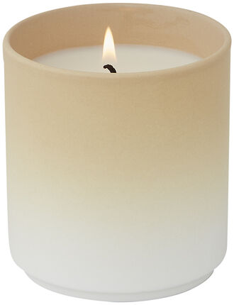 Eine Duftkerze mit dem Namen 'DIP DYE' in einem einfachen und eleganten Design. Die Kerze hat eine beige bis cremefarbene Oberfläche und brennt mit einer ruhigen Flamme.