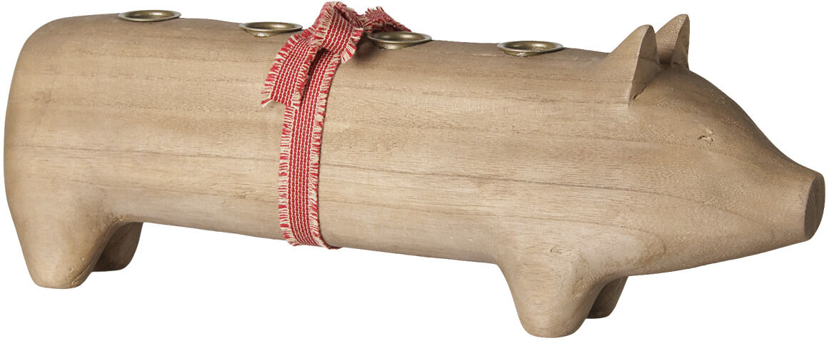 Der abgebildete Kerzenhalter von Maileg zeigt ein großes Schwein komplett aus naturhellfarbenem Holz. Auf seinem Rücken befinden sich vier eingelassene Halterungen für Kerzen, um den Körper ist ein rotes Stoffband gebunden. Das Design ist schlicht und freundlich.