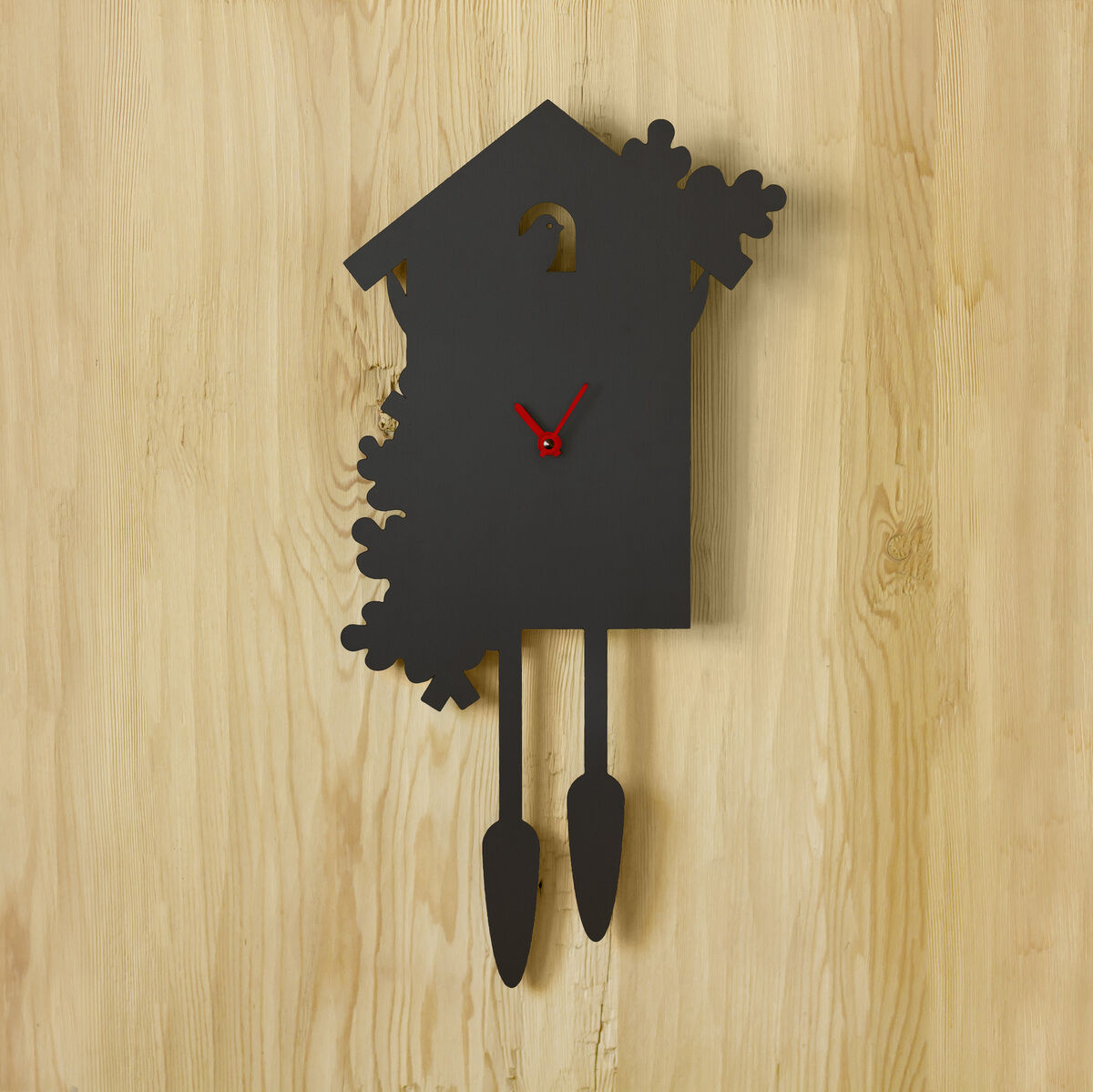 Eine moderne Wanduhr in Schwarz mit rotem Sekundenzeiger und Pendel in Hausform an einer Holzwand montiert.