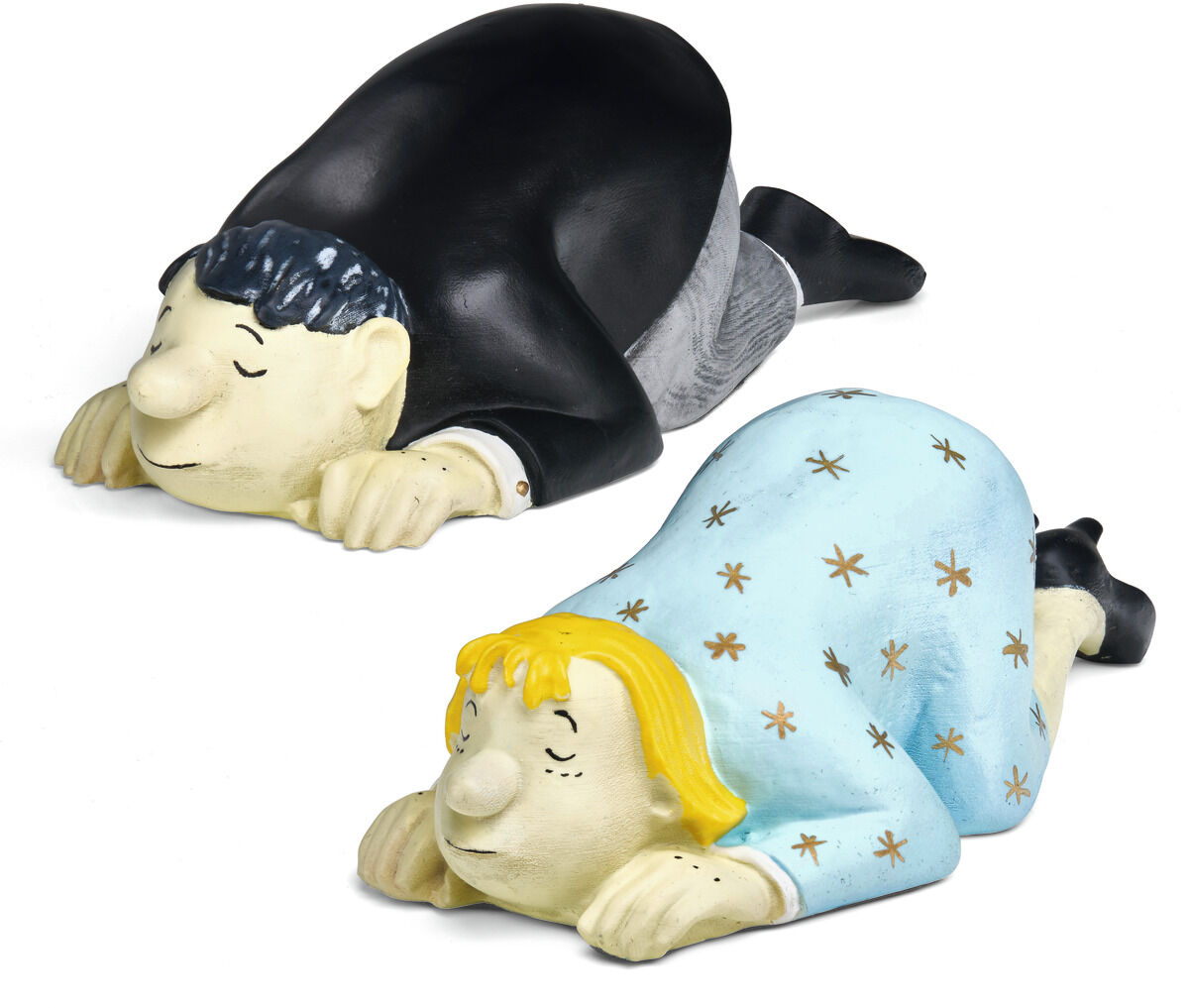 Zwei farbige Skulpturen in Kunstguss, liegend mit nach unten geneigtem Kopf. Eine Figur, der Mann,  trägt schwarzen Anzug und graue Hose. Die blonde Frau einen hellblauen Sternenmantel.