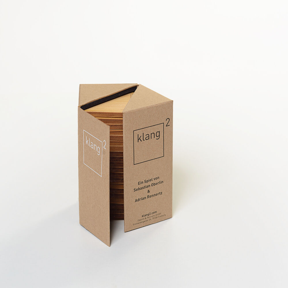 Das Bild zeigt ein Produkt namens „klang² Spielesammlung »Geigenbauer«“. Es besteht aus einer schlichten, braunen Holzkiste. Die Vorderseite der Kiste trägt die Aufschrift „klang²“ und weist darauf hin, dass es sich um ein Spiel von Sebastian Reimertz handelt. Die Verpackung ist minimalistisch gestaltet und aus Naturmaterialien gefertigt.