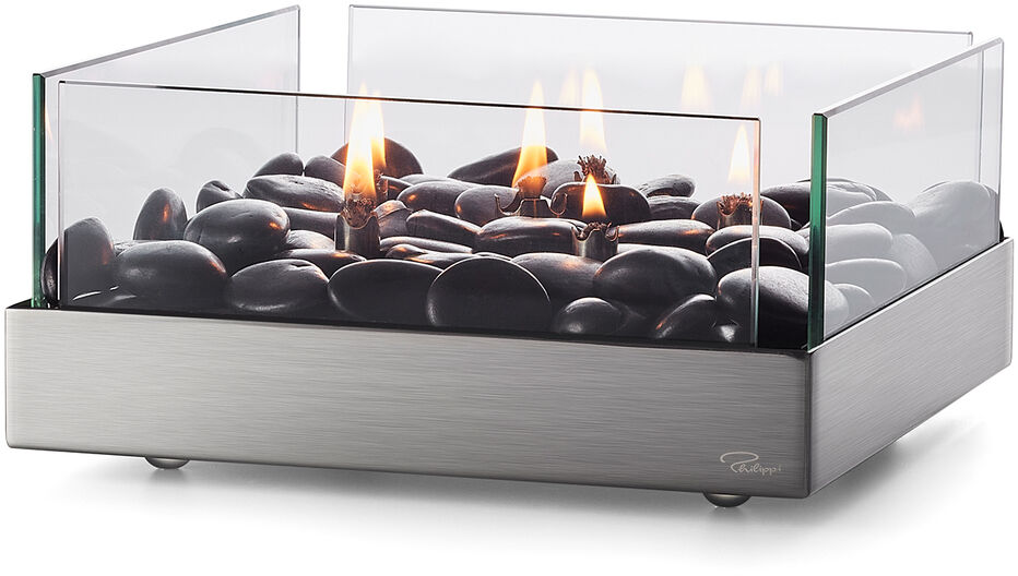 Ein moderner Tischkamin »Fireplace« mit einem Sockel aus Edelstahl und einem gläsernen Schutz. Darin befinden sich schwarze Steine, auf denen mehrere kleine Flammen brennen. Ideal als dekoratives Element für Wohnräume.