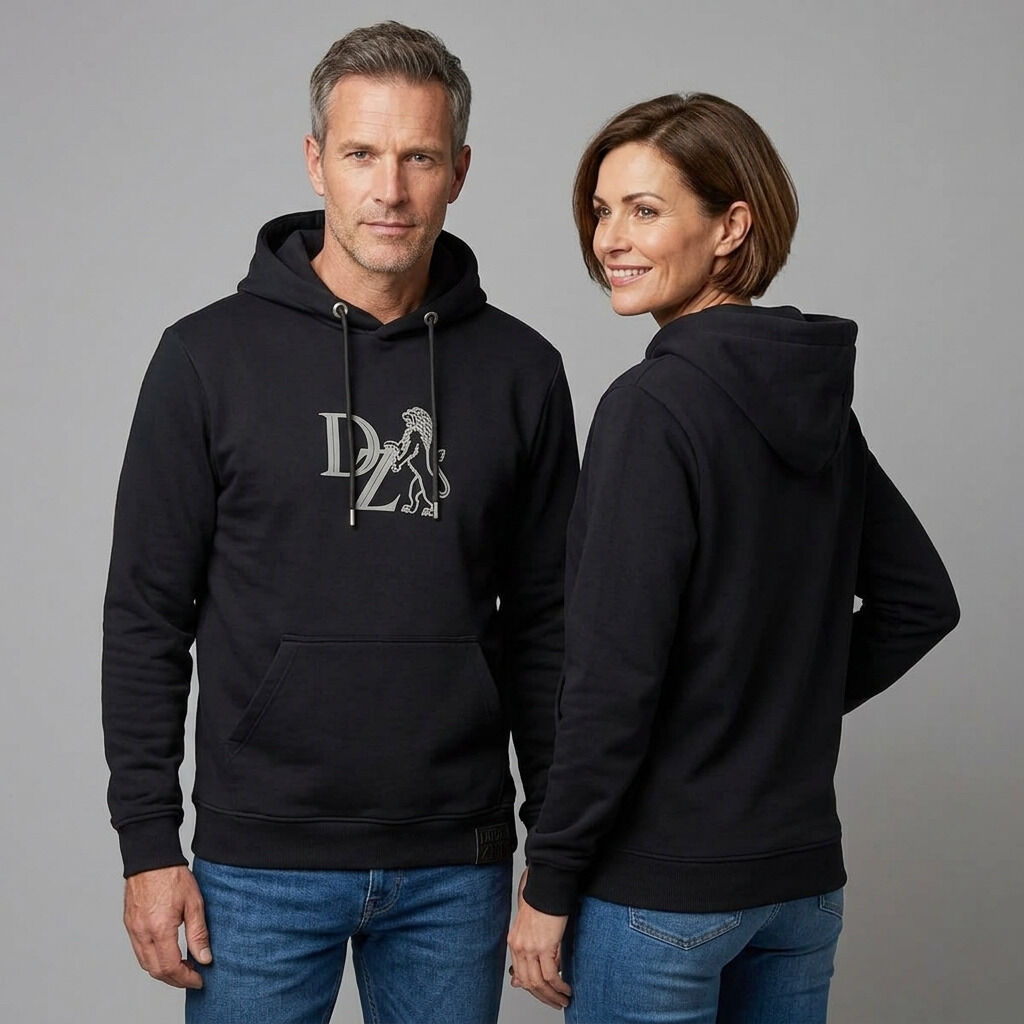 Zwei Erwachsene präsentieren den schwarzen »ZEIT« Hoodie aus der ZEIT-Kollektion. Der Hoodie zeigt einen grauen Schaumprint mit ZEIT-Löwen auf der Brust, hat geprägte Ösen und schwarze Kordeln. Das Material wirkt weich und hochwertig, der Hintergrund ist neutral grau.