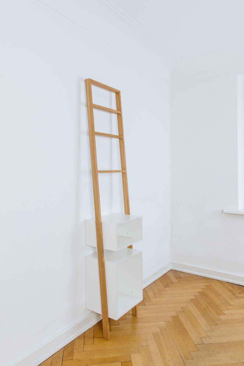 Leiterregal »brecht« aus Holz und Weiß in einem minimalistischen Design. Das Regal lehnt gegen eine weiße Wand auf einem Holzboden und verfügt über zwei Regalflächen zur Aufbewahrung.