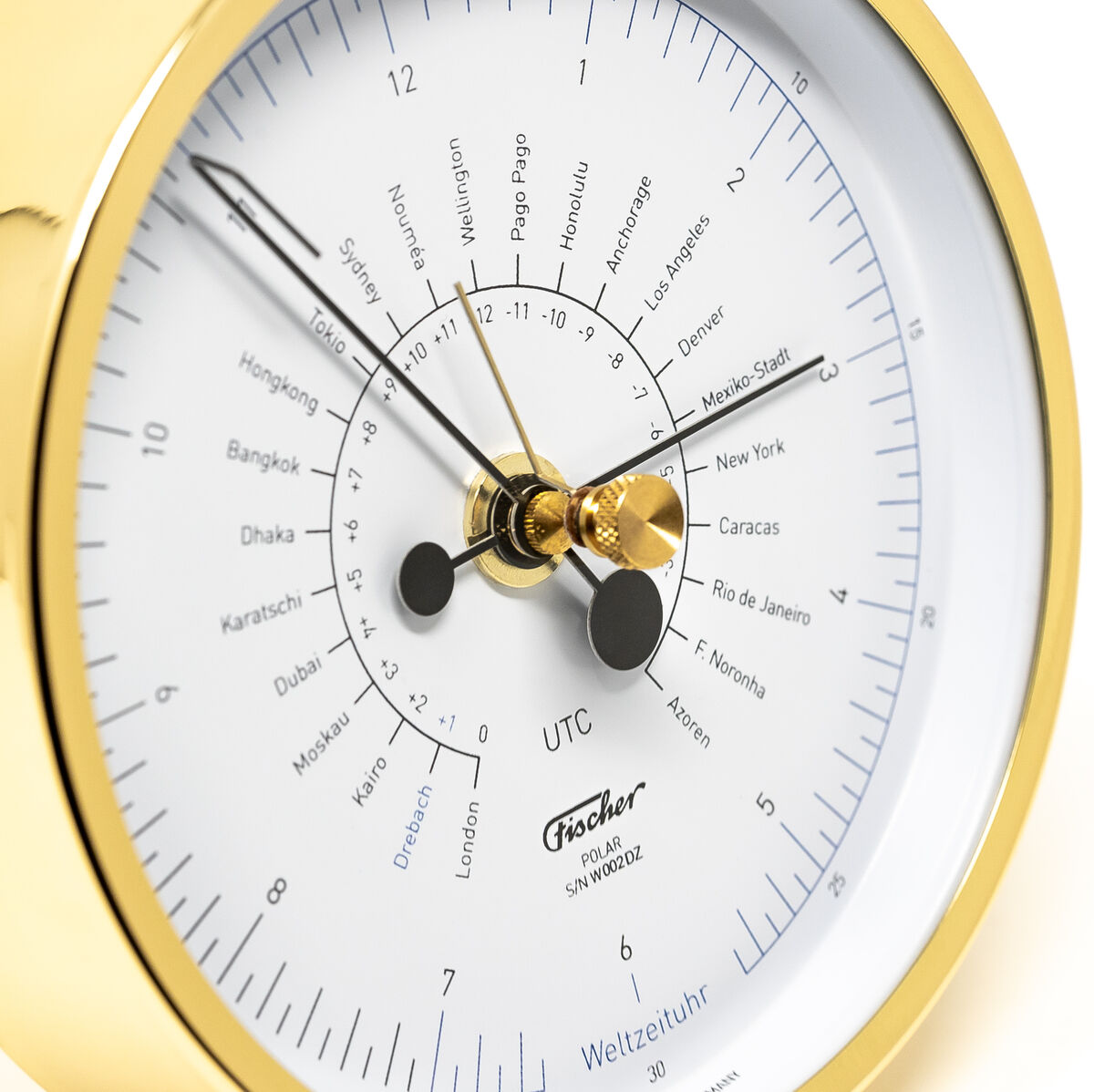 Die ZEIT-Sonderedition »POLAR Weltzeituhr« von Fischer Manufaktur zeigt eine präzise Zeitanzeige mit einem klaren weißen Zifferblatt, umrahmt von einem eleganten goldfarbenen Gehäuse. Die Uhr hat schwarze Zeiger und städtische Markierungen für verschiedene Zeitzonen auf der Welt.