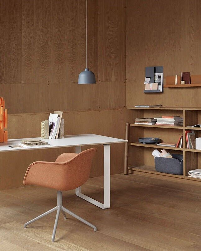 Ein modernes Home Office mit einem weißen Schreibtisch, einem orangefarbenen Stuhl und einem Regal aus Holz mit Büchern und einem Aufbewahrungskorb »Restore«.