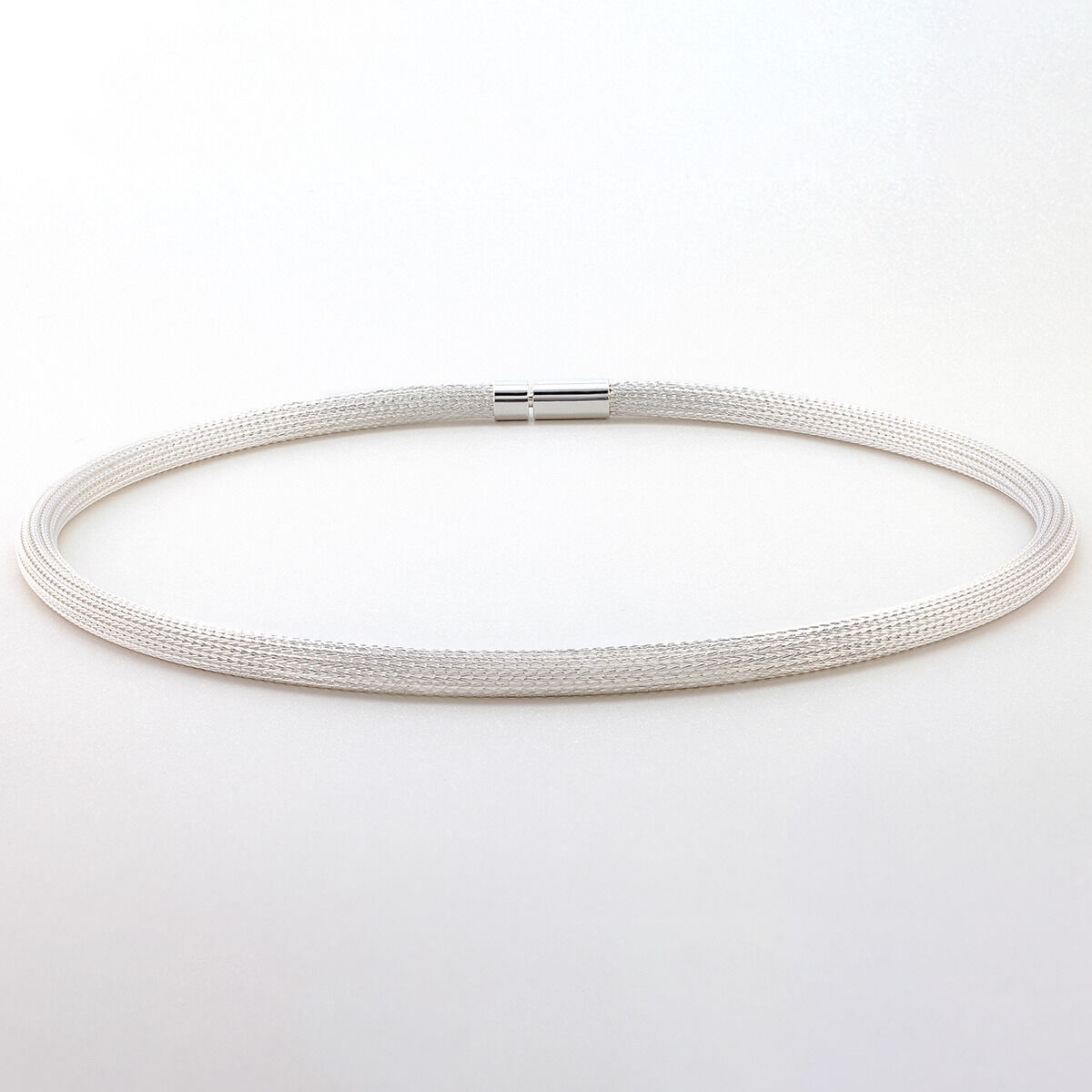 Das Bild zeigt das Collier »Milanaise« von Menard aus feinsten 925er Silberdrähten. Die handgefertigte Kette besitzt ein edles, rundes Strumpfgeflecht ohne Naht und eine glatte, anschmiegsame Oberfläche. Die Kette liegt leicht gewölbt auf hellem Untergrund.