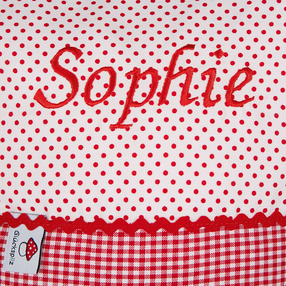 Namenskissen »Schaf« in Rot und Weiß mit dem Namen Sophie aufgestickt. Das Kissen hat ein gepunktetes und kariertes Muster sowie eine dekorative Einfassung.