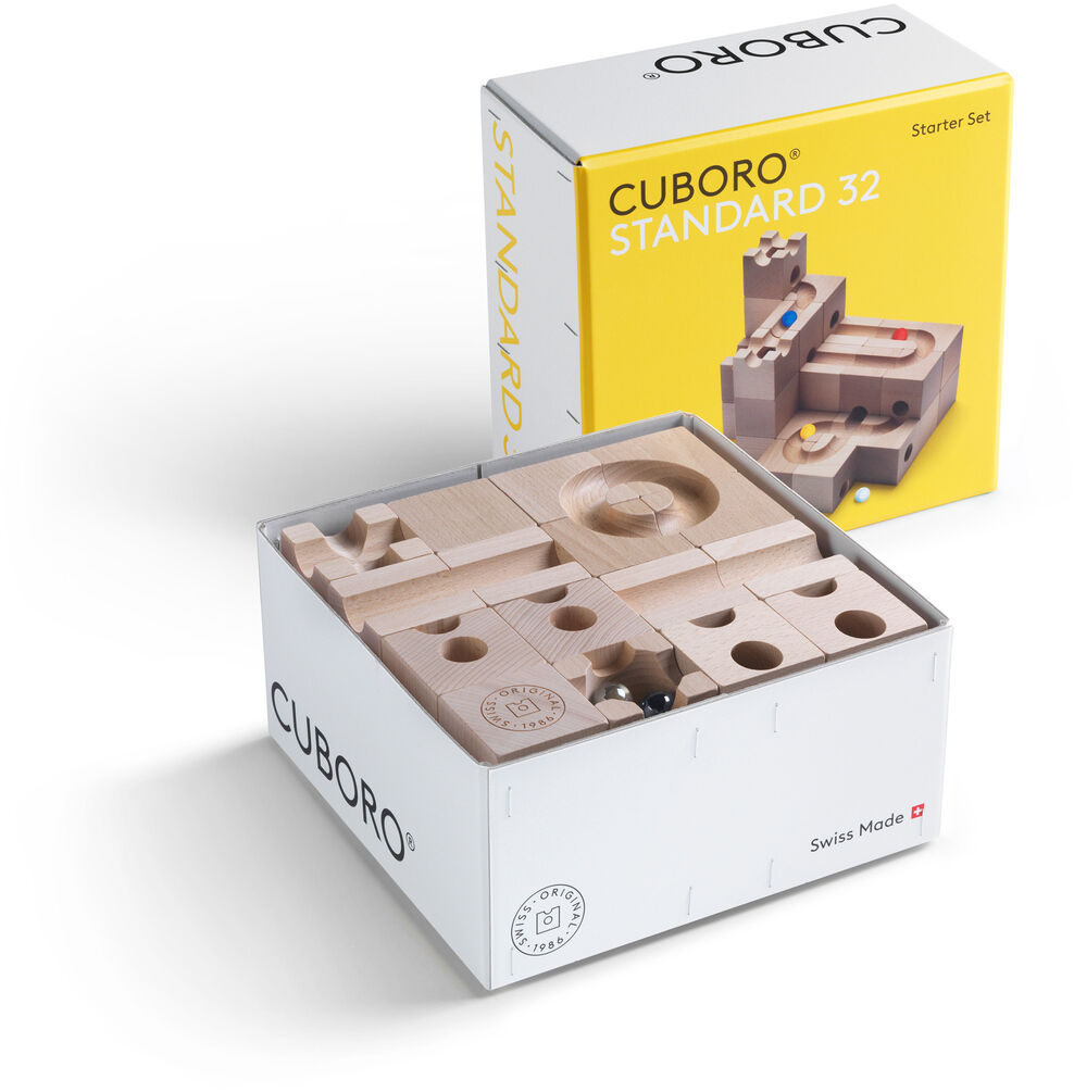 Kugelbahn Starter-Set »STANDARD« in einer weißen und gelben Verpackung. Der Bausatz besteht aus Holzelementen, die verschiedene Bahnen und Strukturen für Murmeln bilden. Auf der Verpackung sind Bilder und Beschreibungen des Inhalts abgebildet.