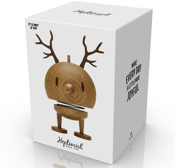 Die Abbildung zeigt eine Verpackung mit einer Hoptimist Rentier Bumble Figur aus Eiche. Die Figur hat einen minimalistischen, skandinavischen Stil mit runden Formen, Geweih und freundlichem Gesicht. Die Verpackung ist überwiegend weiß mit puristischem Druck und Produktabbildung.