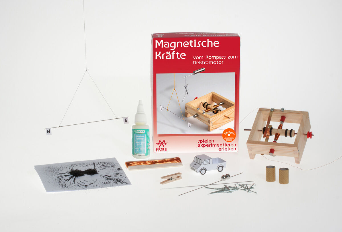 Ein Experimentierkasten mit dem Titel »Magnetische Kräfte«, der eine rote Verpackung, verschiedene experimentelle Werkzeuge, Magnete, eine Spritzflasche, eine Anleitung, Schrauben, einen kleinen Karton, eine Miniatur-Autoattrappe und einige Kugellager enthält.