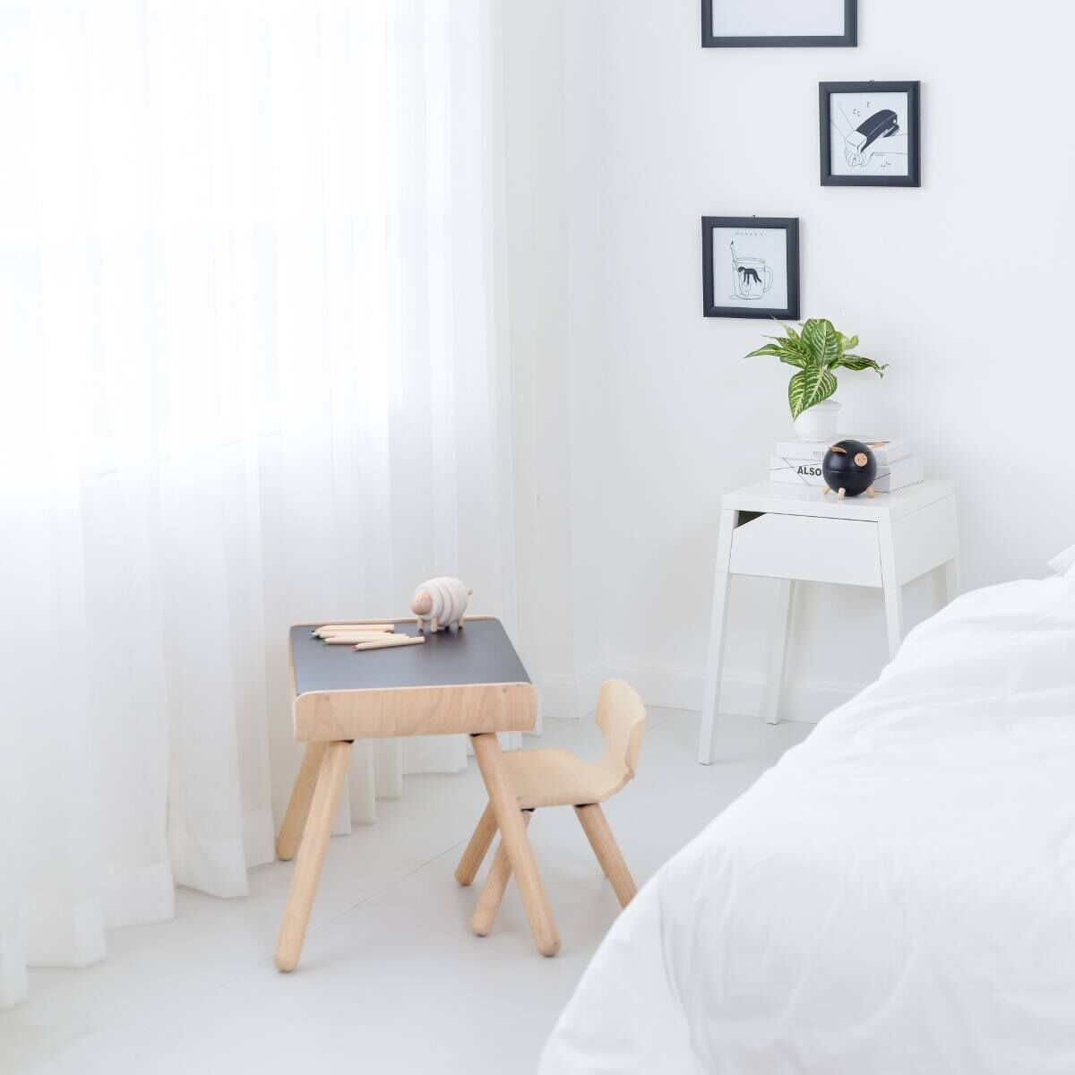 Kleiner schwarzer Tisch mit dazu passendem Stuhl in einem minimalistischen, hellen Raum mit weißen Wänden und Holzboden.