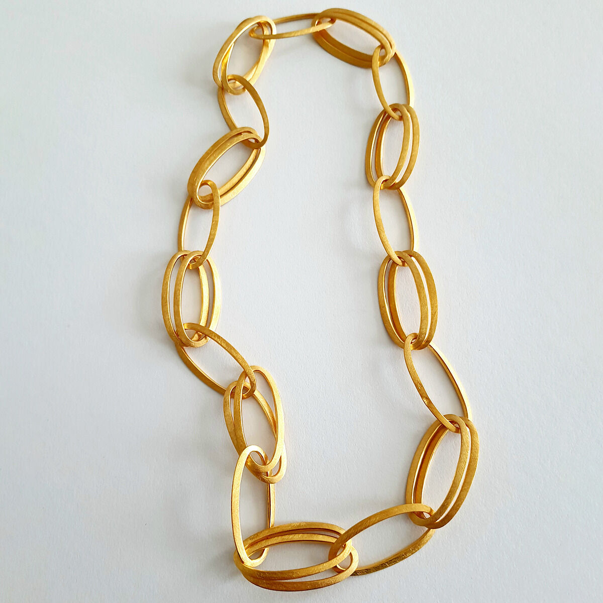 Das Bild zeigt das Collier »GRACE« von HML Berlin, handgefertigt aus 925er Silber und feingoldplattiert. Die Kette besteht aus großen, ovalen, goldfarbenen Gliedern und liegt auf weißem Untergrund. Das Design wirkt edel, modern und puristisch.