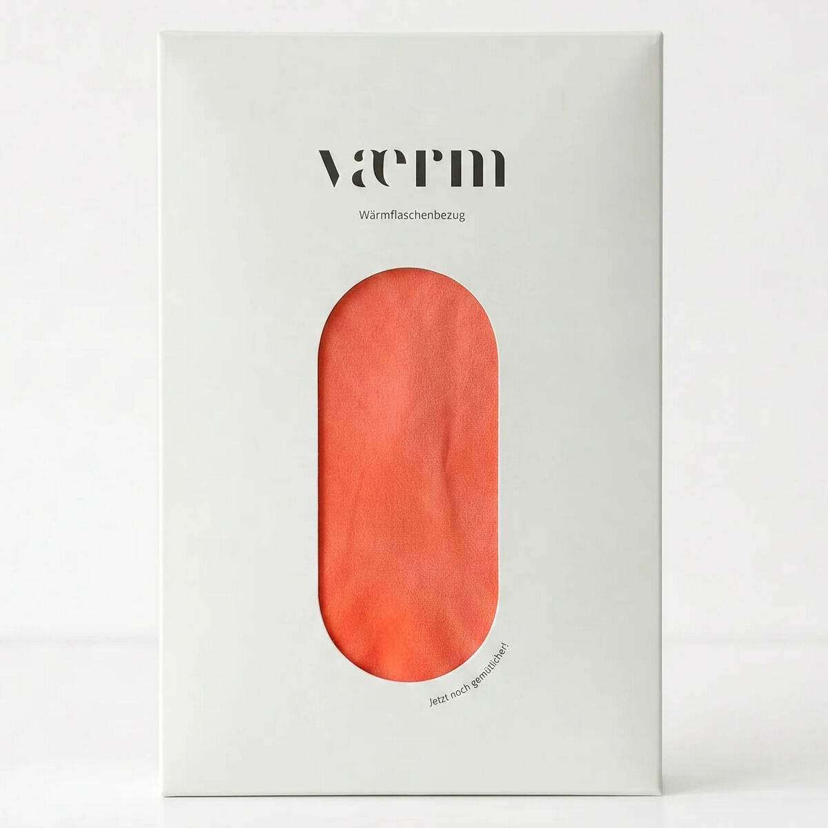 Die Verpackung des VAERM Bezugs für Wärmflaschen in der Farbe Coralle ist schlicht weiß mit einem Sichtfenster, das den korallfarbenen Stoff zeigt. Oben steht der Markenname, darunter Produktbeschreibung. Der Bezug wirkt weich und hochwertig.