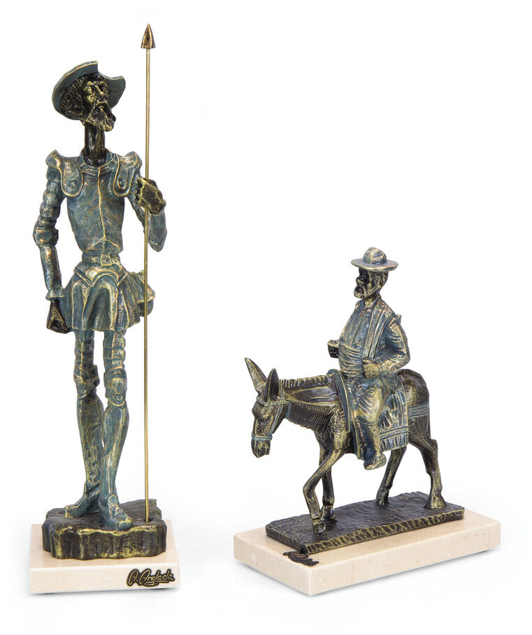 Angeles Anglada Skulptur »Don Quijote« zeigt zwei Figuren: eine stehende Figur von Don Quijote in grüner Bronzeoptik, die ein Speer hält, und eine sitzende Figur auf einem Esel. Beide sind detailreich gearbeitet und stehen auf weißen Sockeln.