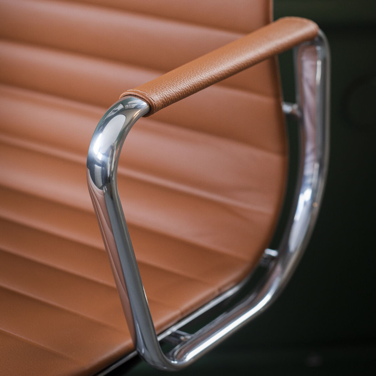 Nahaufnahme eines Vitra Alu Chair EA 118 mit poliertem Rahmen und brauner Lederpolsterung