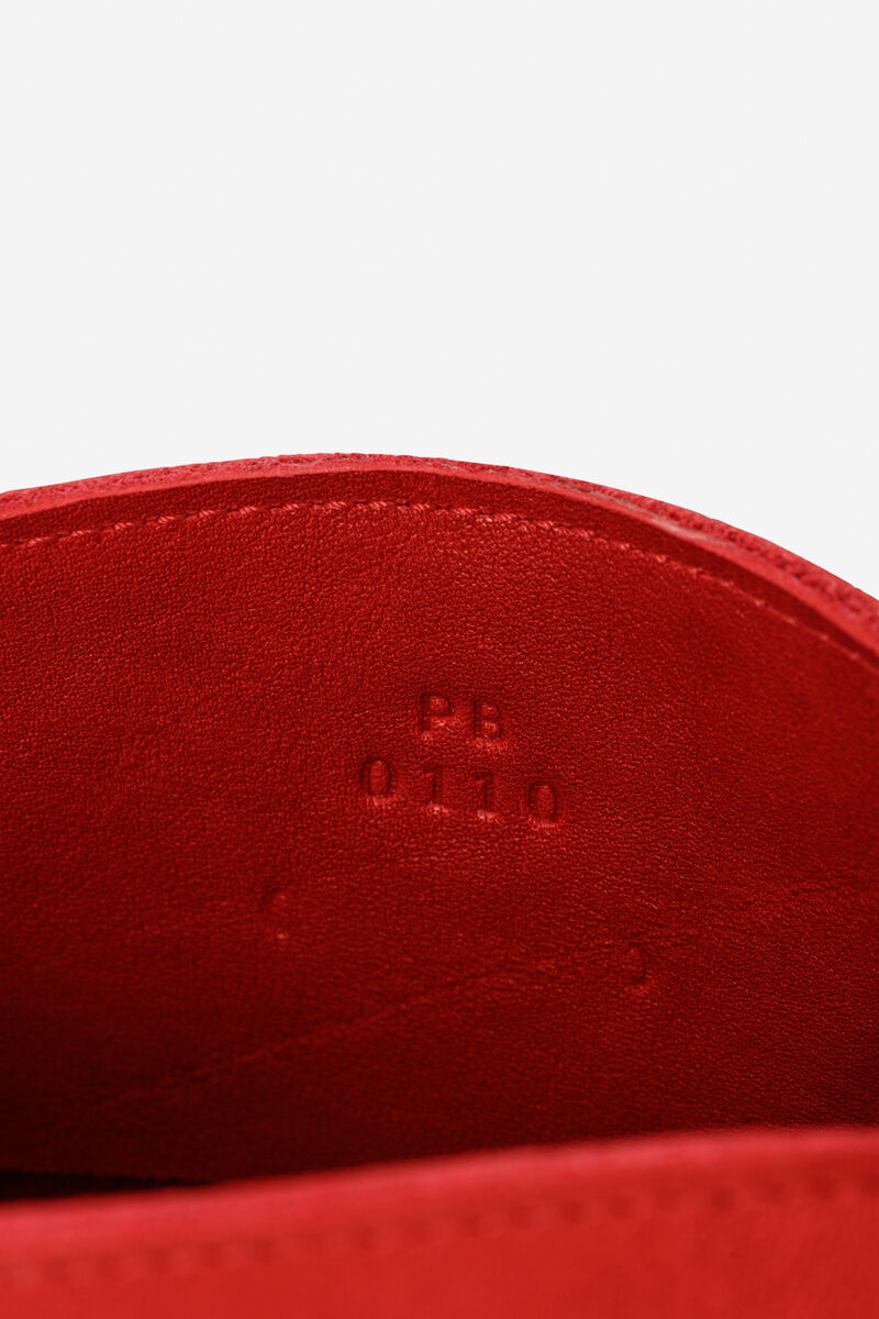 Innenansicht einer roten Lederhandtasche mit der Prägung 'PB 0110'. Die Tasche hat eine glatte und hochwertige Lederstruktur.
