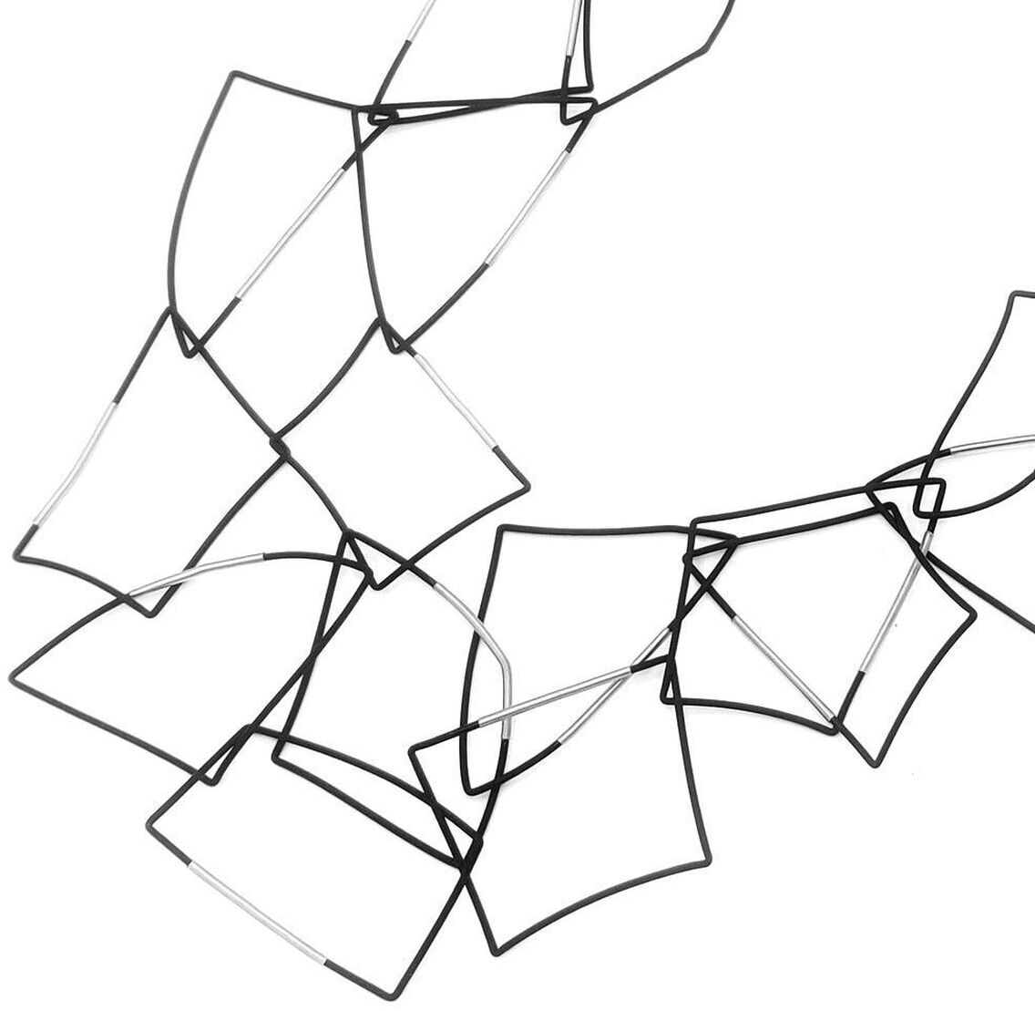 Freigestellte Produktaufnahme der schwarzen Kette »Morphos« von Rosalba Galati auf weißem Grund. Ein langer, flexibel geschwungener Strang aus dünnem PVC mit Stahlkern formt einen offenen Ring. Entlang des Strangs überlagern sich zahlreiche unregelmäßige, kantige Schlaufen und polygonale Linien zu einer luftigen, skulpturalen Struktur.