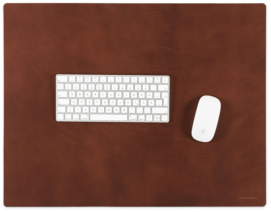 Diese Schreibtischunterlage in Cognac bietet eine elegante Lederoberfläche, die optimalen Schutz und Stil für Ihre Büroumgebung gewährleistet. Sie ist mit einer weißen Tastatur und einer weißen Maus darauf abgebildet, perfekt für das Homeoffice oder den professionellen Arbeitsplatz.