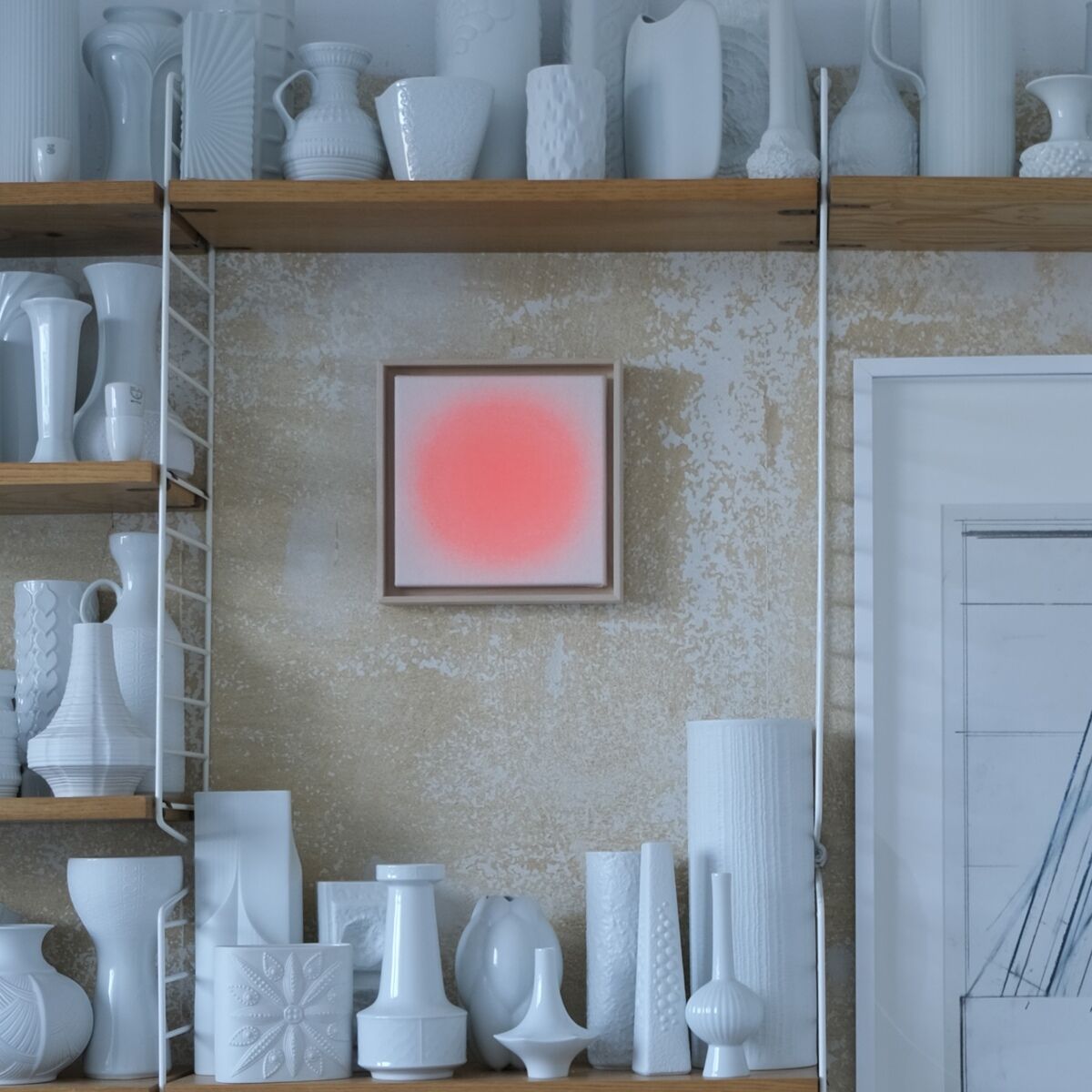 Wand mit Holzregalen, die zahlreiche weiße Keramikvasen und Gefäße präsentieren. Zentral hängt ein gerahmtes Unikat der ZEIT-Sonderedition »Sorbet«, Apricot von Anastasia Benko, das zart apricotfarben leuchtet. Dezente, skandinavisch inspirierte Dekoration dominiert die Szene.