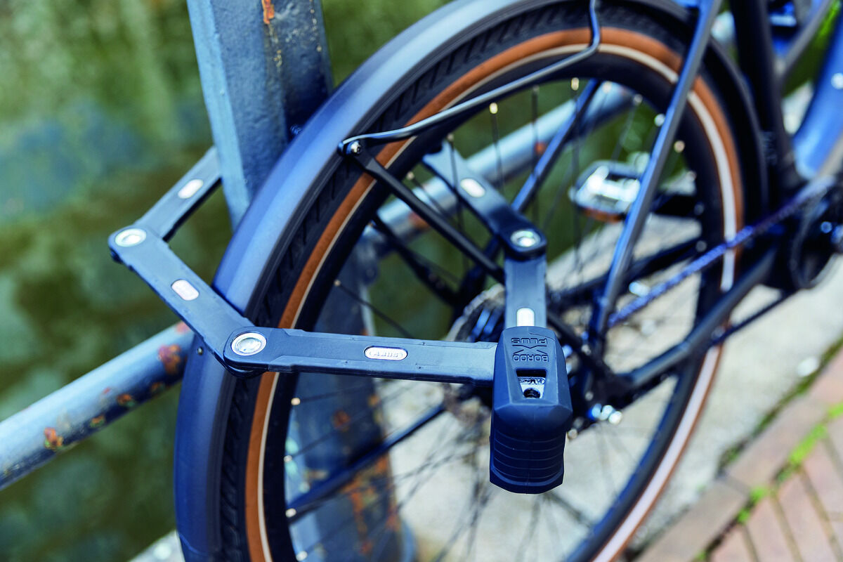 Das Bild zeigt ein Fahrrad mit einem an den Rahmen befestigten Faltschloss »BORDO GRANIT XPlus 6500«. Das Schloss ist schwarz und aus robustem Stahl gefertigt.