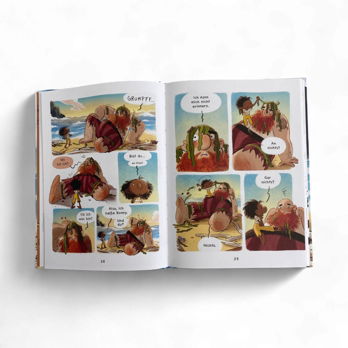 Comic-Doppelseite aus „Zack“ von Volker Schmitt und Màriam Ben-Arab: Am Strand liegt ein bärtiger Mann mit Seetang vor einem Kind. Gesprächsblasen zeigen deren Dialog. Helle, kräftige Farben, Meer, Sand und Küste im Hintergrund, kindgerechter Zeichenstil.