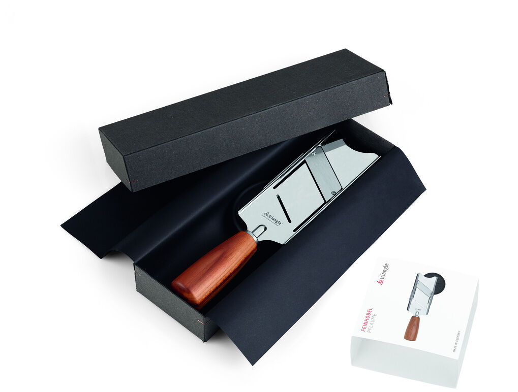 Feinhobel aus Edelstahl und Pflaumenholz in einer schwarzen Geschenkbox, daneben eine weiße Verpackung.