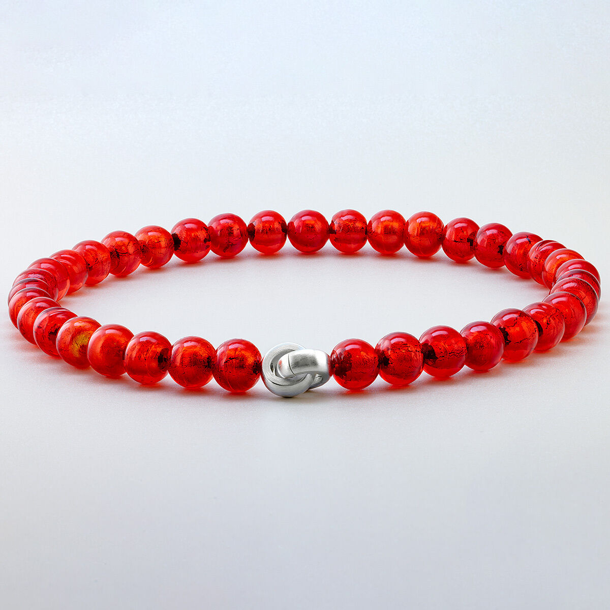 Das Bild zeigt das Collier »Hellrot« Murano von Menard, bestehend aus intensiven, hellroten Muranoglas-Perlen mit einem Durchmesser von 12 mm, harmonisch aneinandergereiht. Die elegante, silberfarbene Schmuckschließe hebt das klassische, handgefertigte Schmuckstück stilvoll hervor.