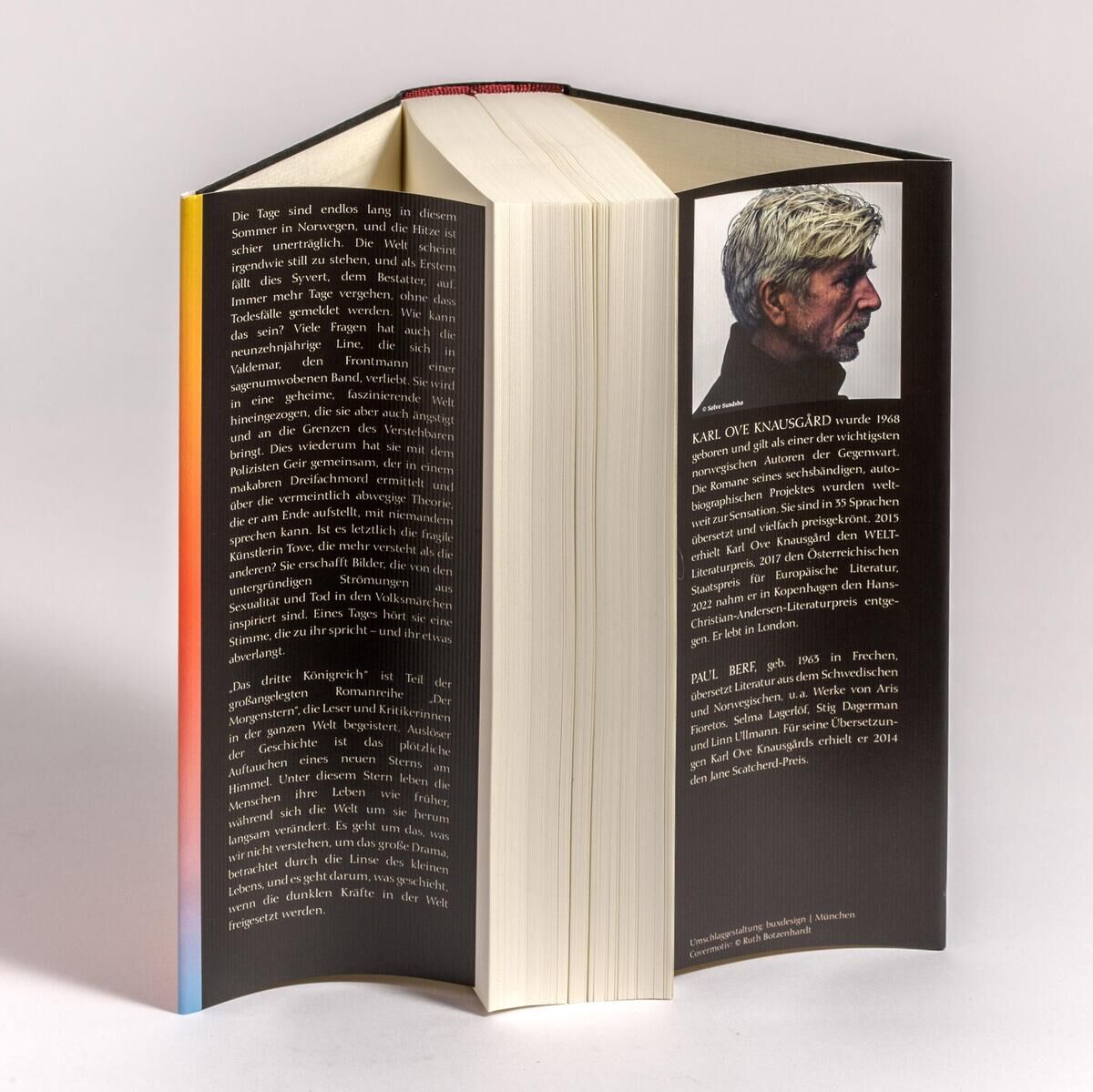Offenes Buch 'Knausgård, K: Das dritte Königreich' mit schwarzem Einband und Autorenporträt auf neutralem Hintergrund.