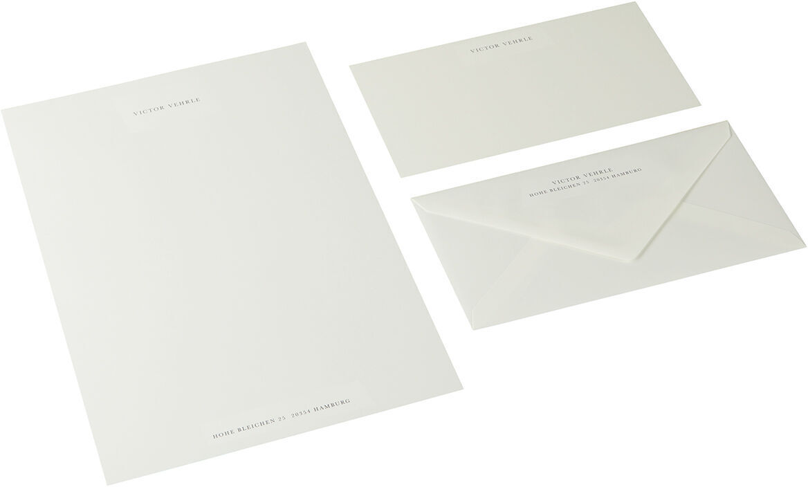 Ein Set von A4-Briefpapier in Anthrazit, bestehend aus einem Briefbogen, einem Umschlag und einer kleineren Karte, auf einem weißen Hintergrund.