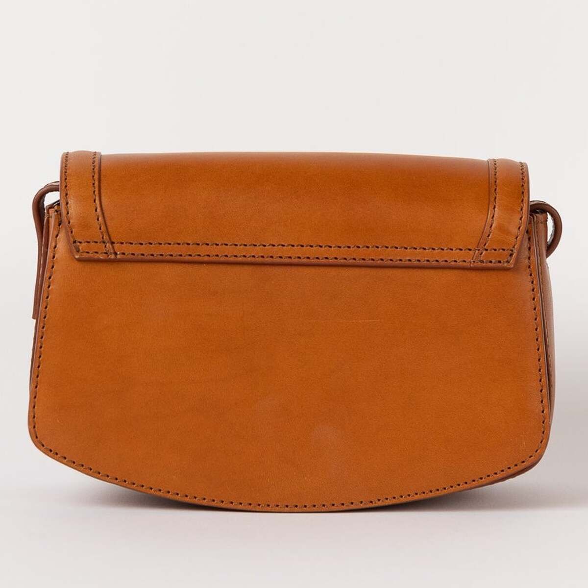 Braune Umhängetasche in Lederoptik mit abgerundeter Form und minimalistischer Gestaltung, stehend vor einem neutralen Hintergrund.