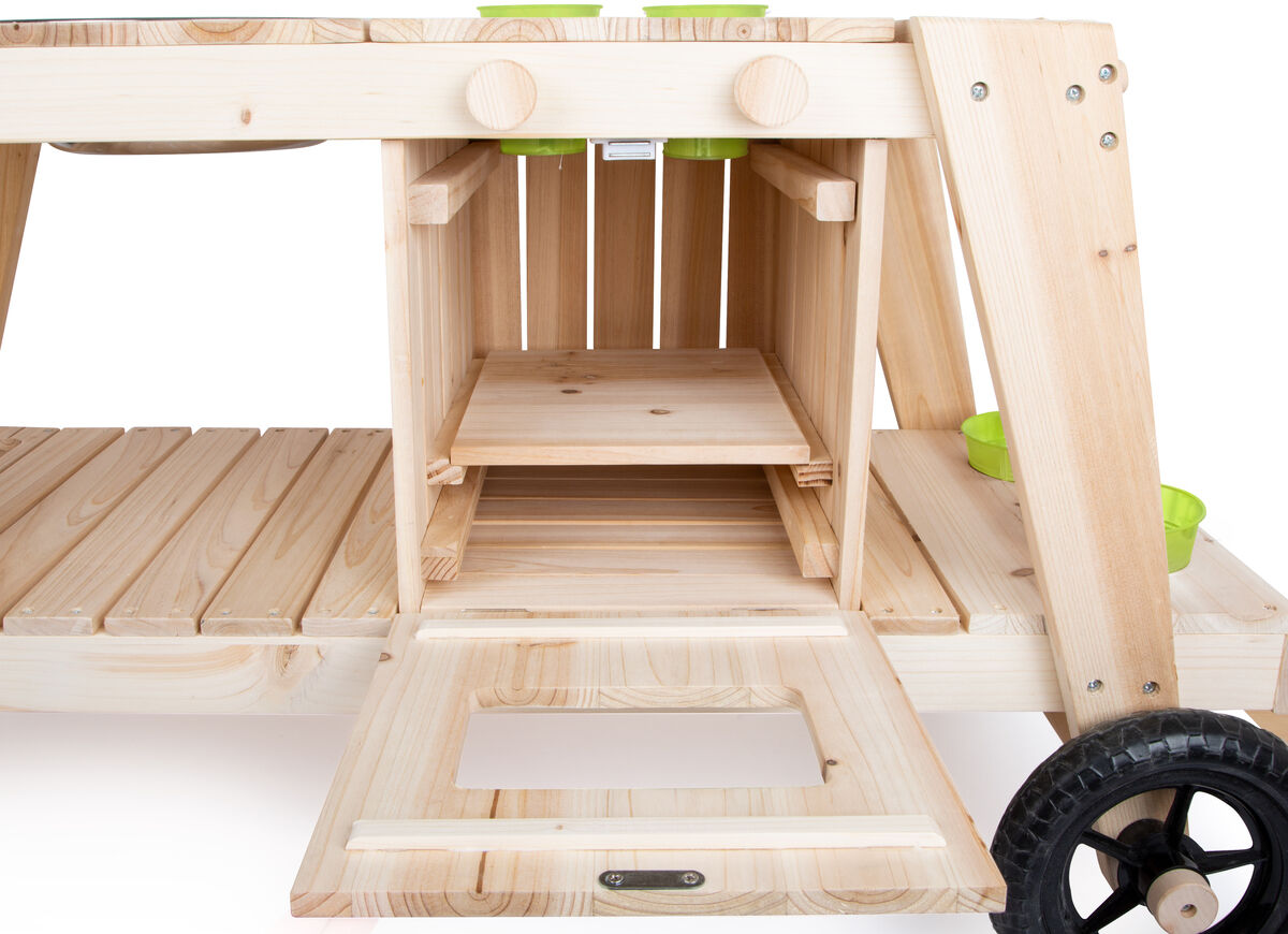 Matschküche für Kinder aus Naturholz mit grünen Plastiktöpfen. Die Küche hat eine Arbeitsfläche, ein Regal und eine Ofentür, dazu Rollen für einfachen Transport. Ideal für Outdoor-Spiel im Garten.