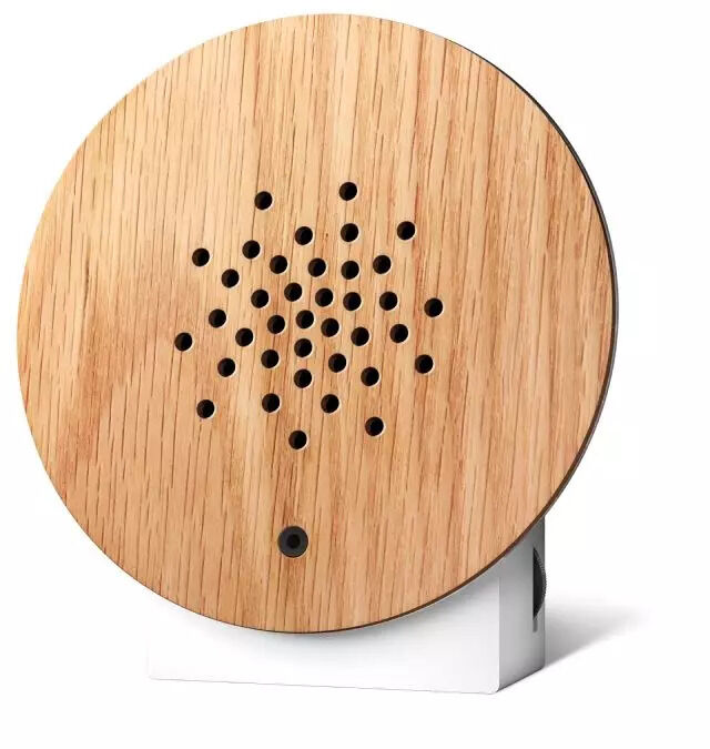 Runder Lautsprecher mit Holzoptik auf einem weißen Sockel, minimalistisches und modernes Design.