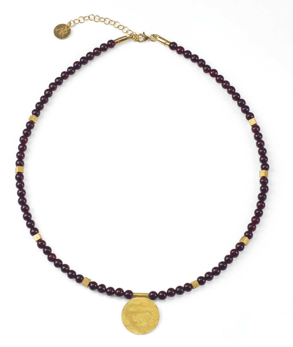 Bernsteincollier »Cassia« aus dunkelvioletten Perlen und goldenen Gliedern mit einem großen, runden, goldfarbenen Anhänger in der Mitte.