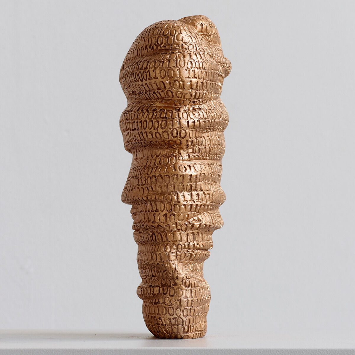 Eine goldene Skulptur mit geprägten Zahlen und Buchstaben, Teil der ZEIT-Jubiläumsedition mit dem Namen »Type Face«, auf einem neutralen Hintergrund platziert.