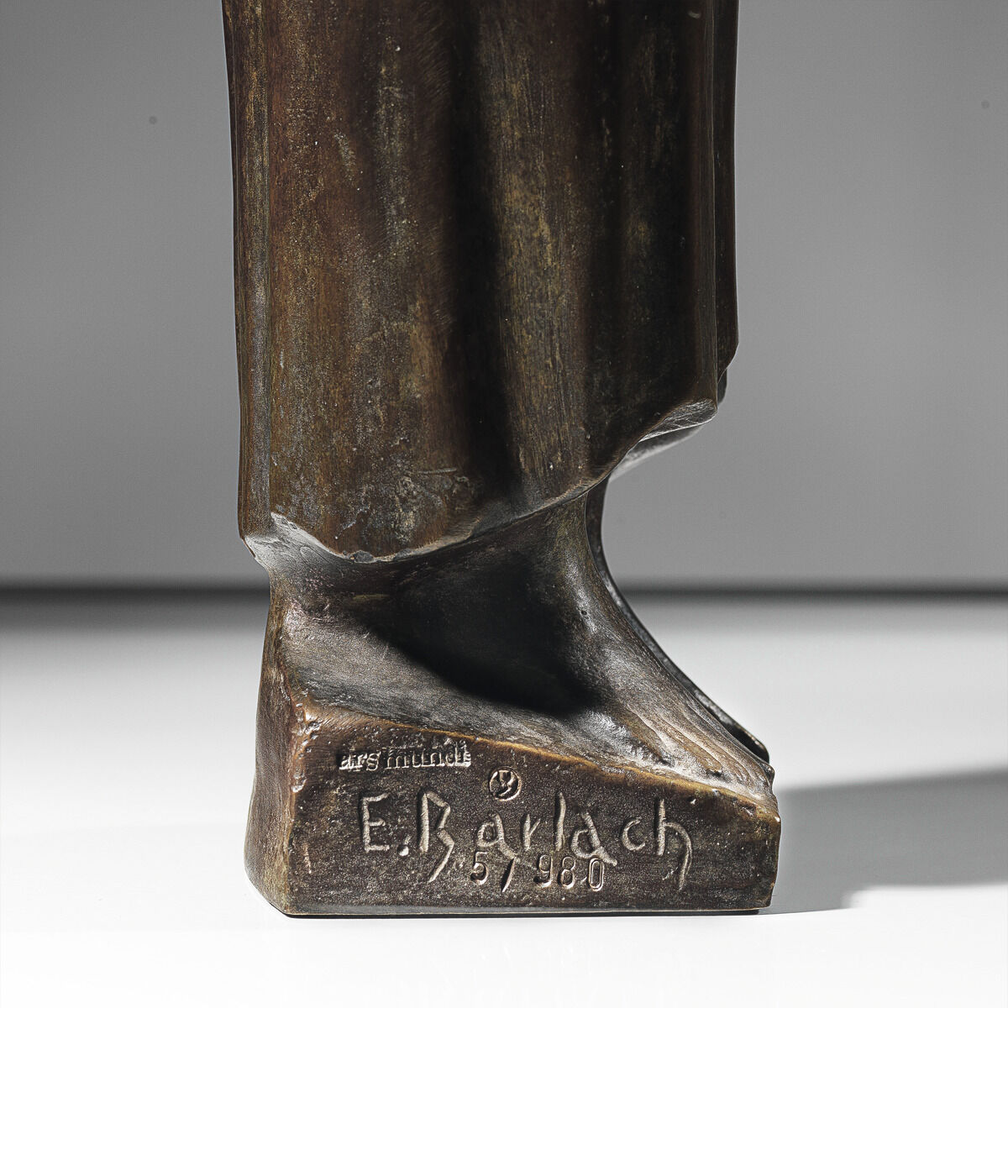 Bronzeskulptur von Ernst Barlach mit dem Titel 'Der Sinnende II' aus dem Jahr 1934. Abgebildet ist der untere Teil einer stehenden Figur, sichtbar ist der Sockel mit eingraviertem Namen 'E. Barlach' und der Jahreszahl '3/5 1980'.