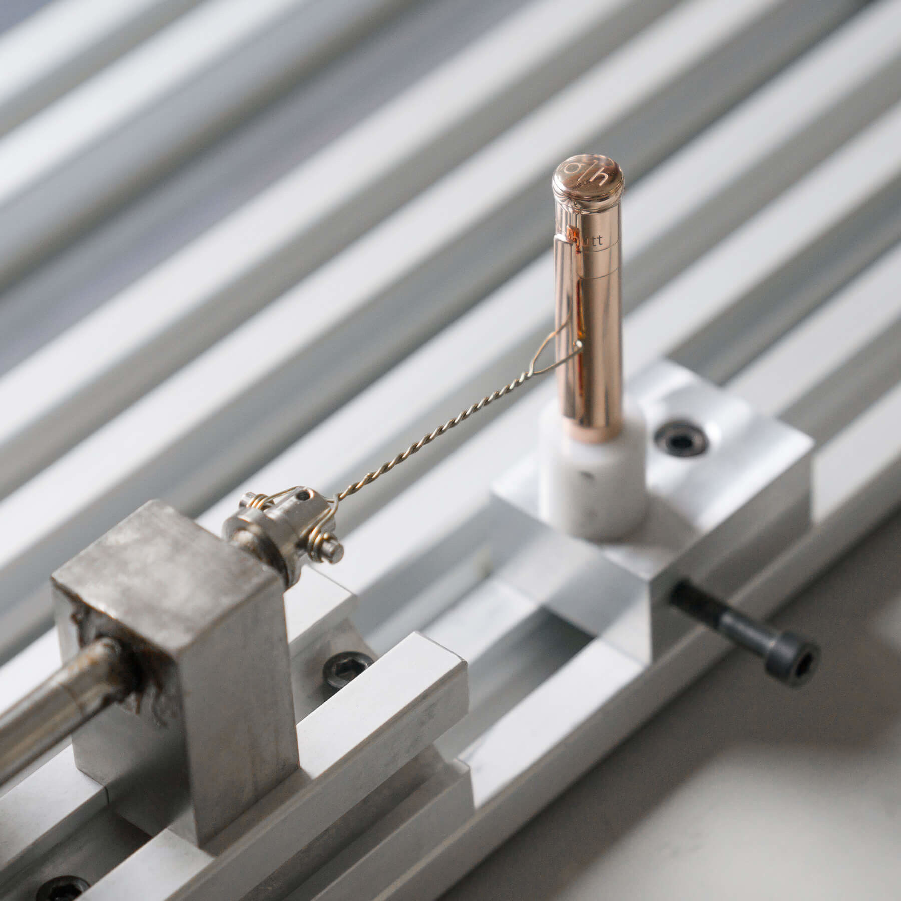 Feinmechanische Vorrichtung mit Draht und zylindrischem Metallteil auf einer Schiene