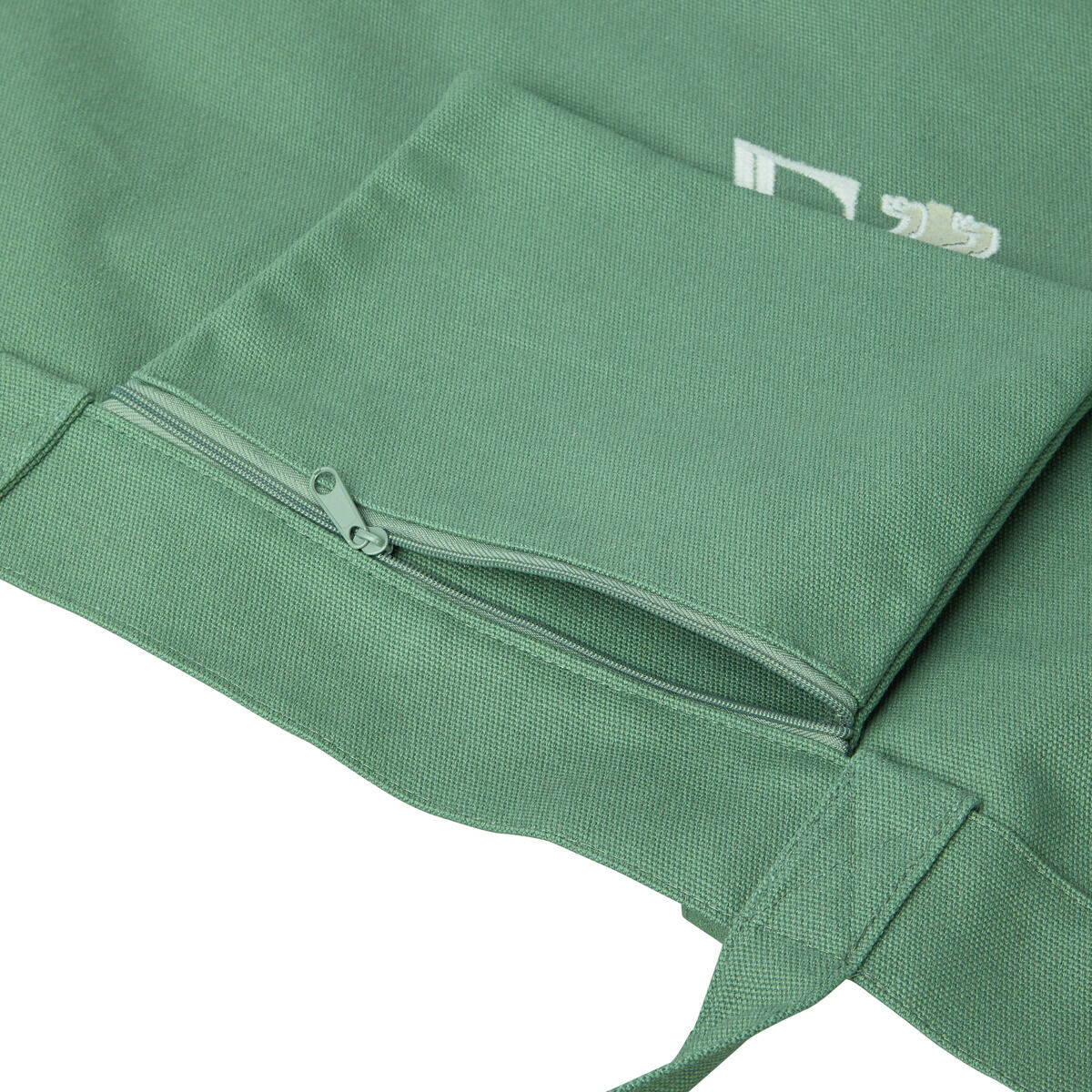 Grüne Canvas-Tasche mit weißen Details. Die Tasche verfügt über eine Außentasche mit Reißverschluss und zwei Tragegriffen. Perfekt für den Alltag, als Einkaufstasche oder für den Strand geeignet.
