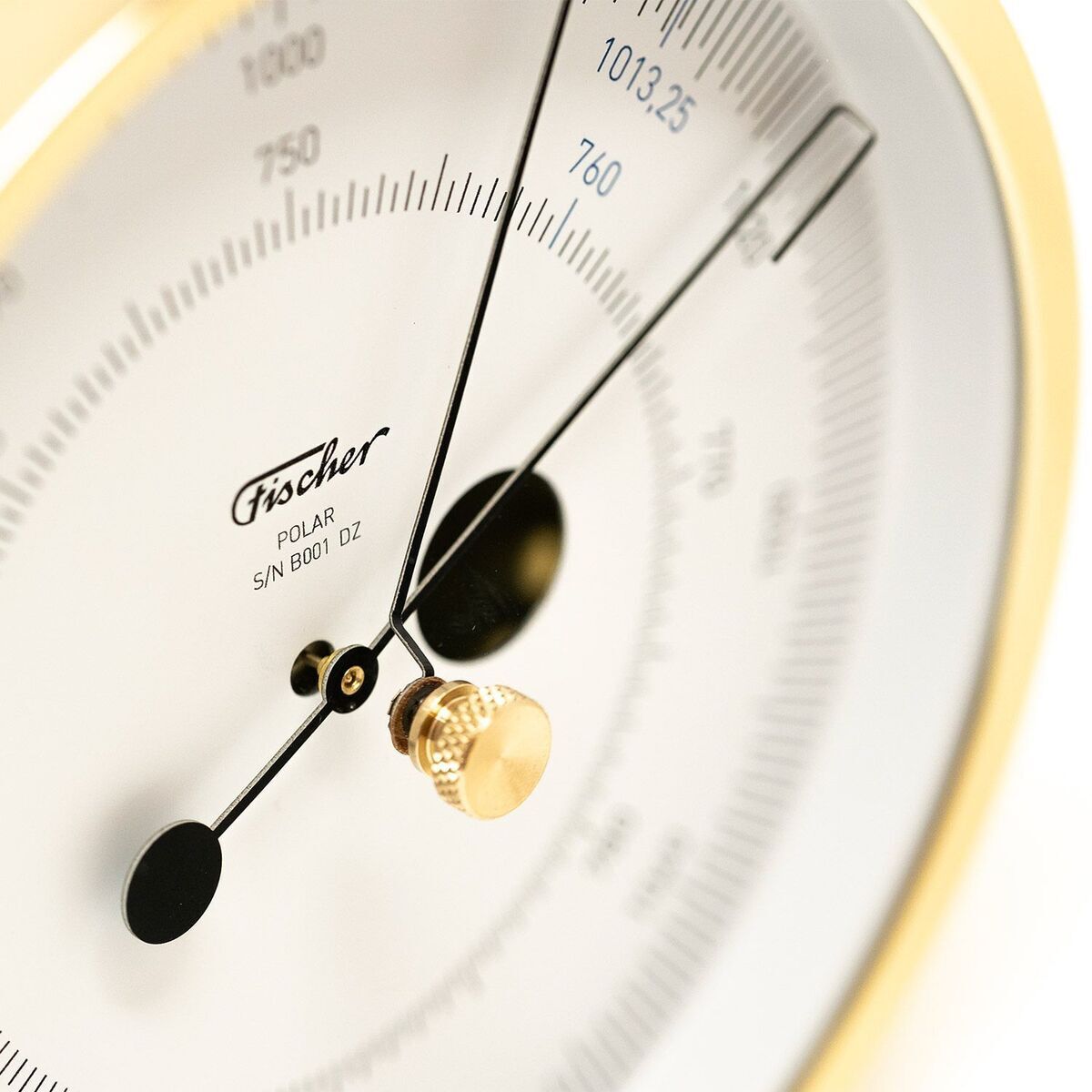 Nahaufnahme eines ZEIT-Sonderedition »POLAR Barometer«. Das Zifferblatt ist weiß mit schwarzen Markierungen und einer goldfarbenen Mitte, an der die Zeiger befestigt sind. Das Barometer hat ein klassisches rundes Design und eine qualitativ hochwertige Ausführung.