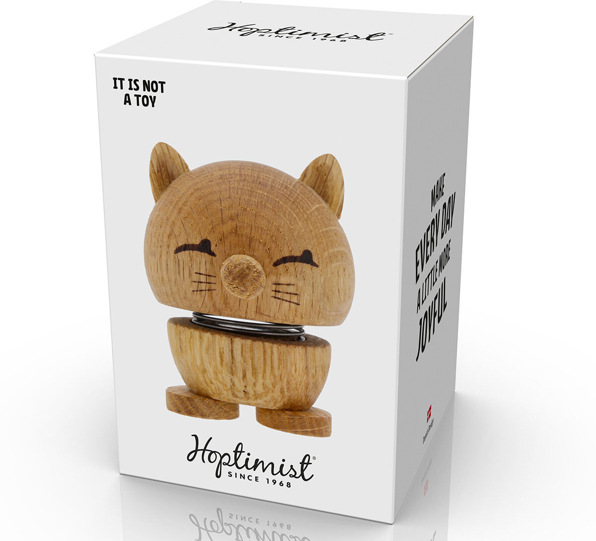 Das Bild zeigt eine Hoptimist Katze aus Eichenholz auf einer Verpackung. Die Figur hat ein niedliches Gesicht mit Schnurrhaaren und sitzt auf einer Metallfeder. Die Verpackung ist in einem minimalistischen Design gehalten.
