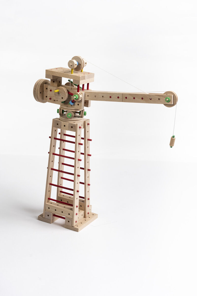 318-teiliges Konstruktionsset aus Holz, genannt »Explorer E318«, bestehend aus verschiedenen Holzstücken und Komponenten, zusammengebaut zu einer kranähnlichen Struktur mit beweglichen Teilen und farbigen Akzenten auf weißem Hintergrund.